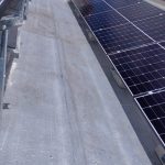Solar panels mounted on a flat roof with cable trunking run along the surface