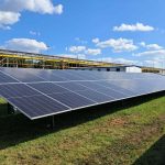 Ground-mounted solar panels on a landscaped area at a commercial premises